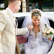 Happy bride and groom exiting limousine.